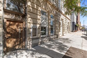 A building with a large wooden door, a brick facade, and a sidewalk. - Cornerstone at Front and Chestnut-We love dogs! (Wilmington)