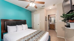 A bedroom with a bed, a ceiling fan, a door, a bathroom, and a TV. - Star Beachside - Marlin Cottages 1 - Beautiful Condo, Family Friendly, Swimming & Kiddie Pool, Spa, Short Walk to the Beach (South Padre Island)