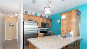 A kitchen with wooden cabinets, stainless steel appliances, a granite countertop, and pendant lighting. - Star Beachside - Marlin Cottages 1 - Beautiful Condo, Family Friendly, Swimming & Kiddie Pool, Spa, Short Walk to the Beach (South Padre Island)