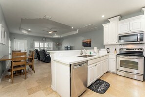 A modern kitchen with white cabinetry, a dishwasher, an oven, and a microwave.