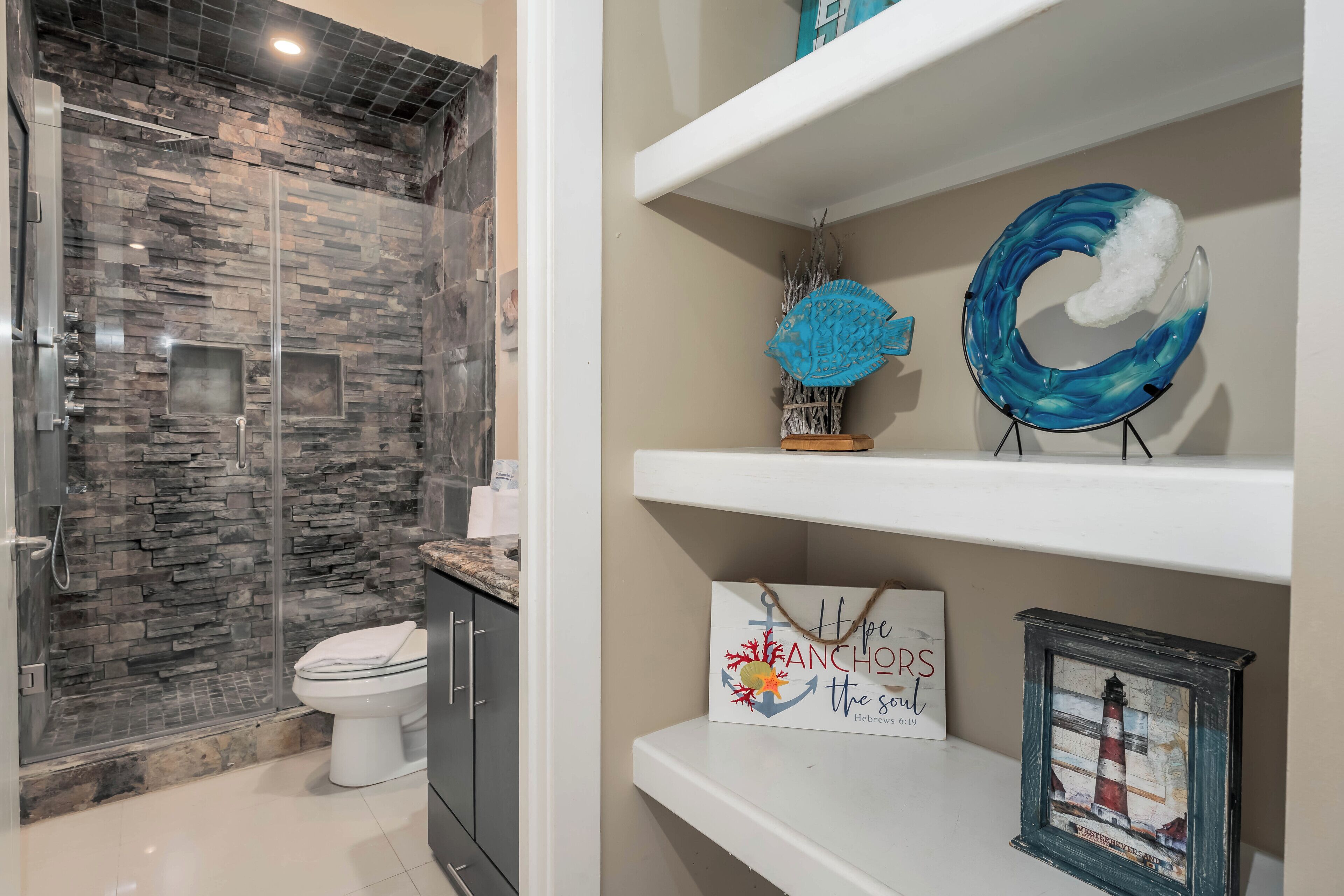 A bathroom with a glass-enclosed shower, a toilet, and a shelf with decorative items.
