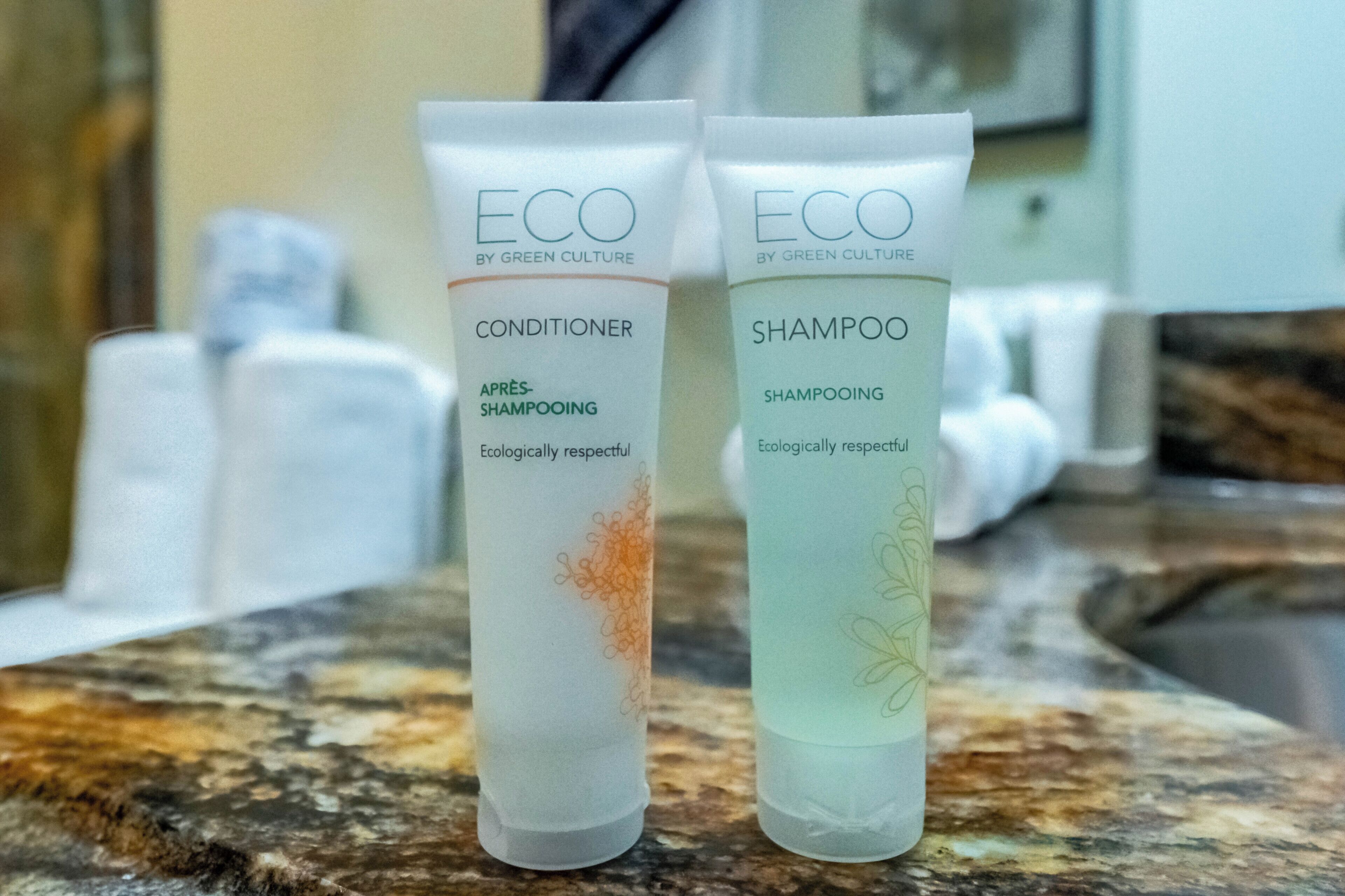 Deux tubes de revitalisant et de shampoing ECO de la marque Green Culture, posés sur un comptoir en marbre.