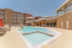 Ein Hotelinnenhof mit Schwimmbecken, Außenmöbeln und mehreren Balkonen.