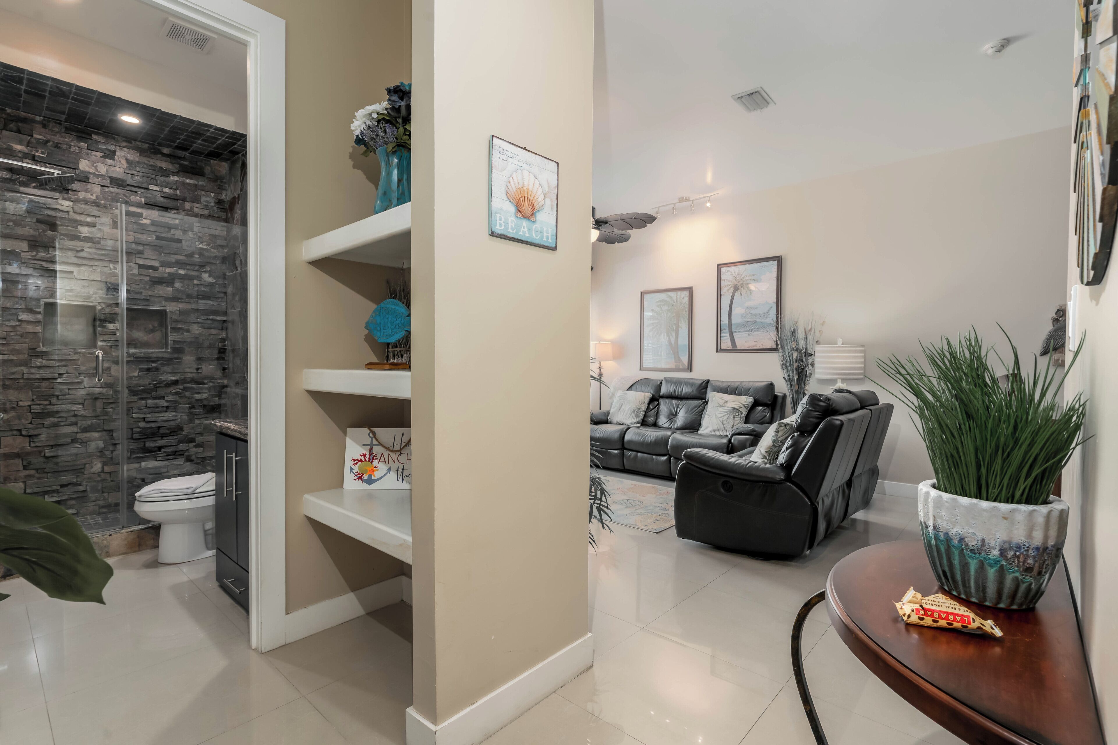 A modern bathroom with a stone backsplash, a toilet, and a shower area.