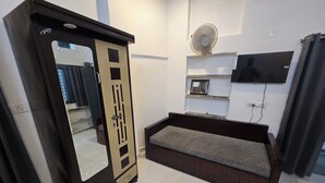 A bedroom with a bed, wardrobe, TV, and a mirror. - Peaceful 1BHK 🌿 WiFi near by GT Mall, Airport” ✅ Jawahar circle malviya nagar (Jaipur)
