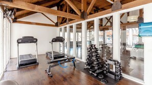 Una palestra con tapis roulant, una cyclette e un espositore di manubri.