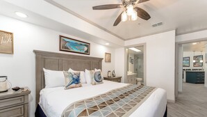 Una camera da letto con un letto grande, un ventilatore a soffitto e vista sul bagno.