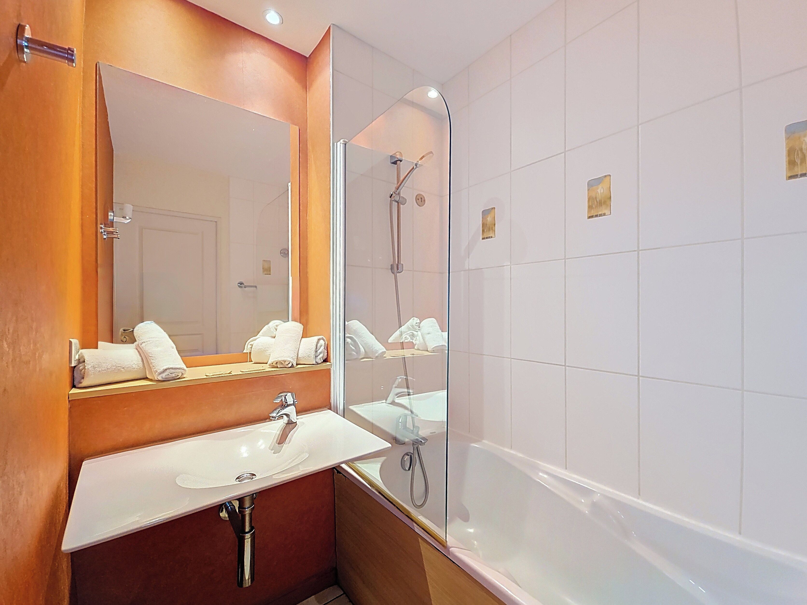 Ein Badezimmer mit Waschbecken, Spiegel, Dusche und Badewanne.