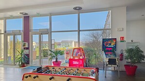 A room with a foosball table, a television screen, and large windows. - Terres de France - Domaine Val d'Amboise (Amboise)