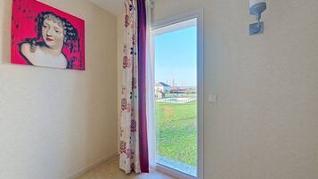 A room with a door leading to a balcony, a painting on the wall, and a security camera.
