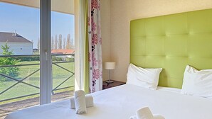 A hotel room with a bed, a nightstand, a lamp, and a view of the outside. - Terres de France - Domaine Val d'Amboise (Amboise)