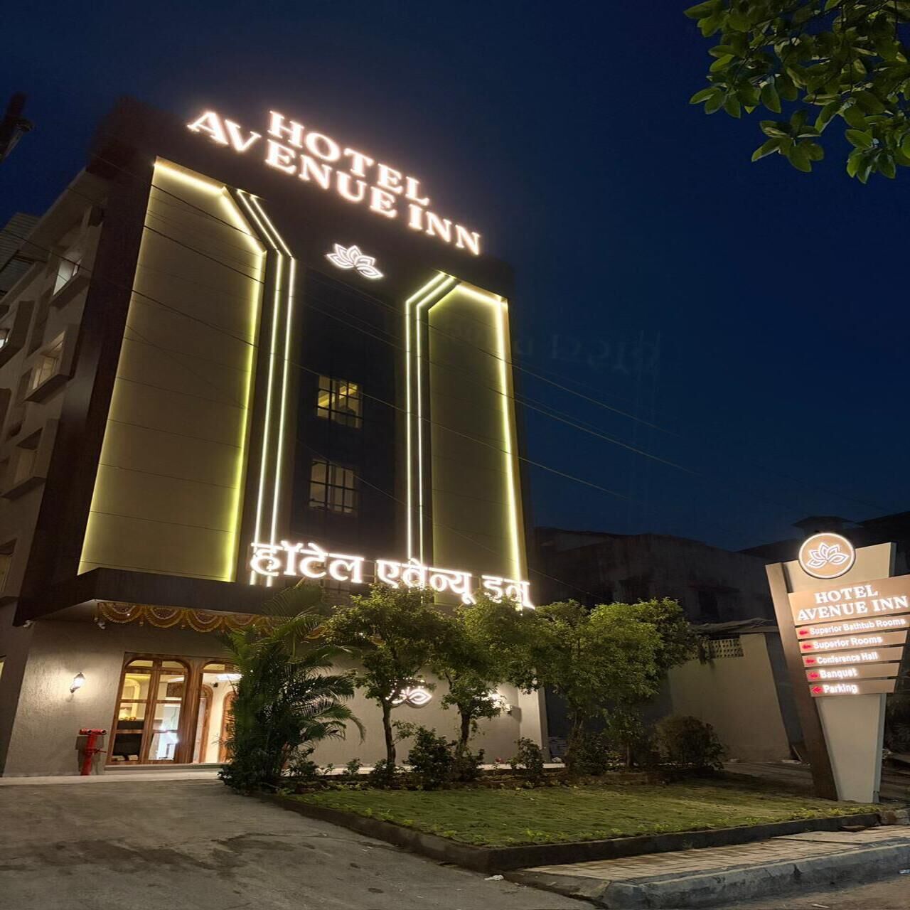 Un hotel llamado 'Hotel Avenue Inn' con un letrero destacado, entrada y un área ajardinada con árboles.