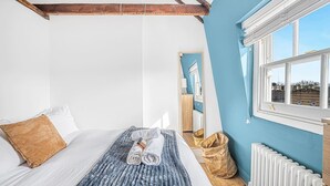 Un dormitorio con cama, ventana, radiador y espejo.
