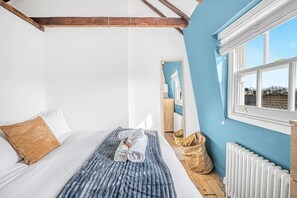 Ein Schlafzimmer mit Bett, Fenster, Heizkörper und Spiegel.