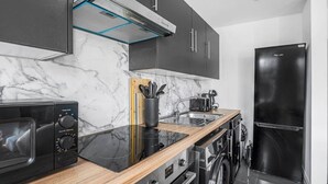 Una cocina moderna con microondas, tostadora, pileta y electrodomésticos de acero inoxidable.