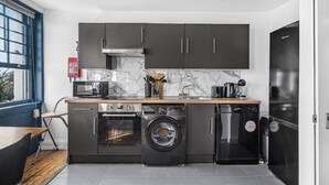 Una cocina funcional con lavadora, lavavajillas, horno y microondas.