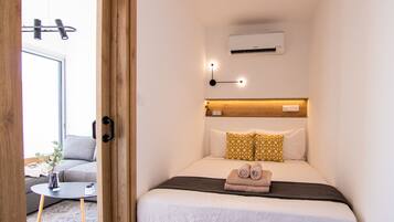 Une chambre d’hôtel compacte comprenant un lit, une table de chevet et un petit coin salon avec un canapé et une table.