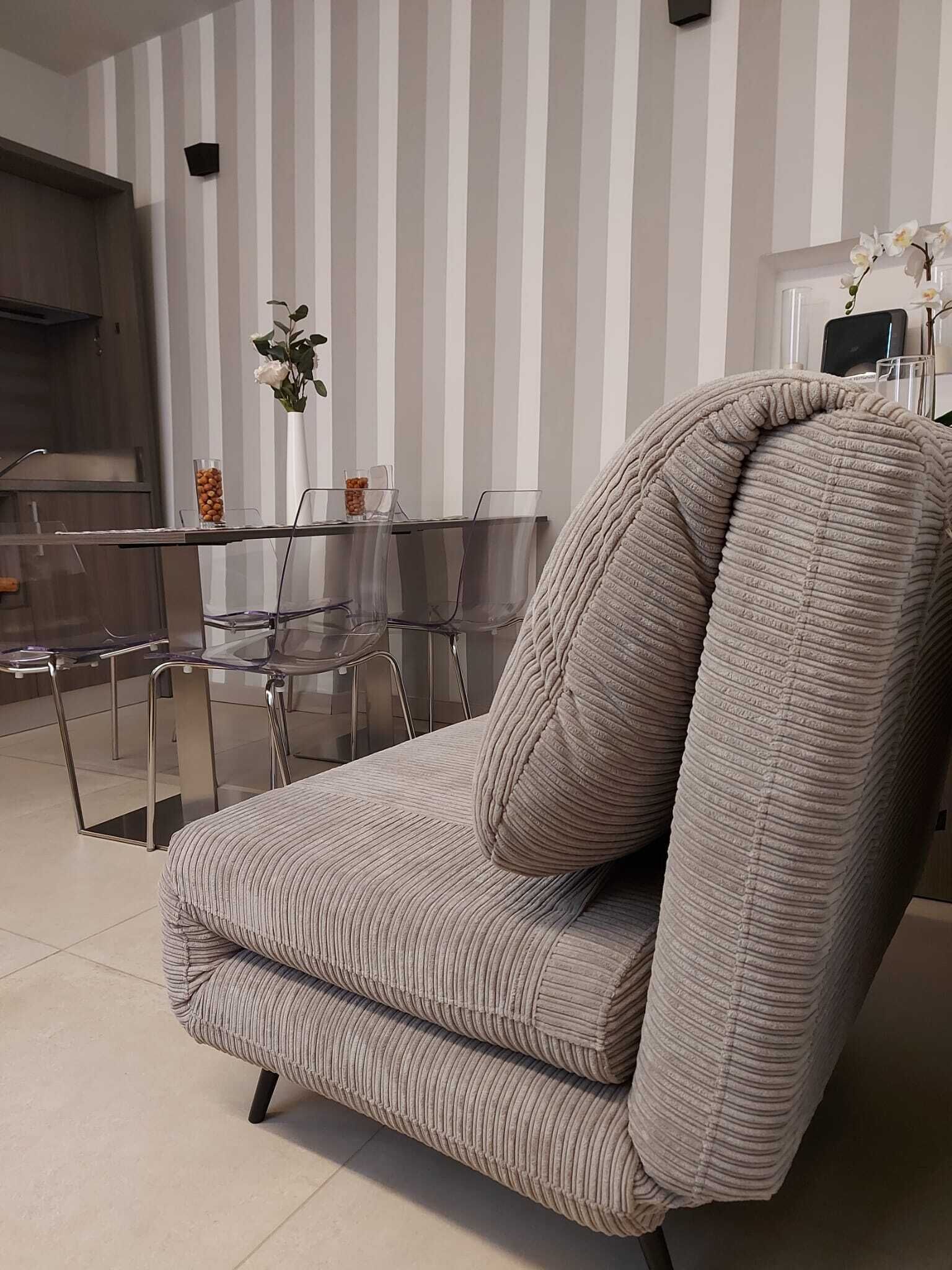 A modern living room with a striped sofa, a glass dining table, and a striped wall.