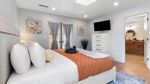 Ein Schlafzimmer mit Bett, Fernseher, Badezimmer mit Spiegel und Küchenzeile.