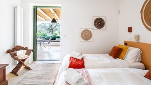 A bedroom with two beds, a wooden chair, a radiator, and a view of the outdoors. - The Ridge House with Sea View by Rentbeat  (Carovigno)