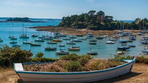 A marina with numerous boats docked, a boat in the foreground, and a building with a tower on a hill in the background. - Accommodation for 4, 500m from the beach (Dinard)