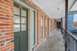 A corridor with a brick exterior, a door labeled '206', and a balcony with a metal railing. - Salt & Serenity | Main Street & Free Parking (Saint Charles)