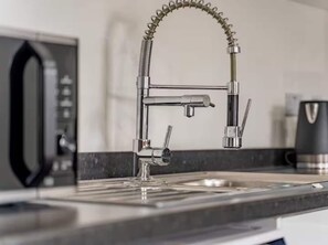 Une cuisine équipée d’un robinet moderne, d’une machine à café et d’un four à micro-ondes.