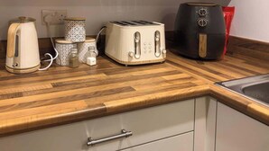 A kitchen with a wooden countertop, a toaster, a kettle, a coffee maker, and a red bag. - Stylish Central Penthouse: Free Parking & Wi-Fi (Derby)