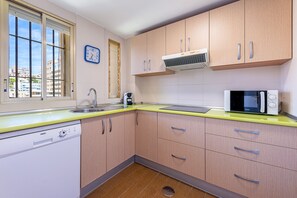 Eine Küche mit Holzausstattung, einer eingebauten Mikrowelle, einem Spülbecken und einem Fenster mit Blick auf Gebäude.