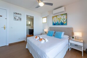 Ein Hotelzimmer mit Bett, Nachttischen, Deckenventilator, Klimaanlage und einem Bild an der Wand.