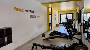 Ein Fitnessraum mit Trainingsgeräten, einer Spiegelwand und motivierenden Texten.