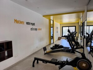 A gym with exercise equipment, a mirrored wall, and motivational text. - Cozy apartment with swimming pool and gym (Dakar)
