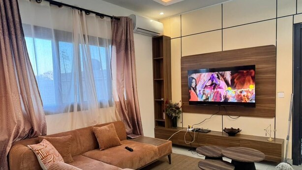 Ein modernes Wohnzimmer mit Sofa, Fernseher und Couchtisch.