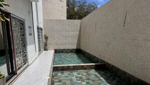 Ein Innenhof mit Pool, Fliesenboden und Backsteinmauer.
