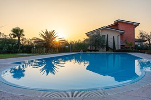 Ein Pool mit Spiegelung von Palmen und einem Gebäude mit roter Fassade.