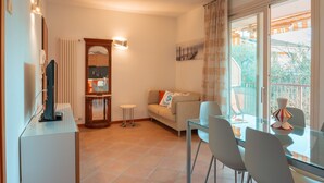 Un salon avec un canapé, une table à manger en verre et un téléviseur posé sur un meuble.