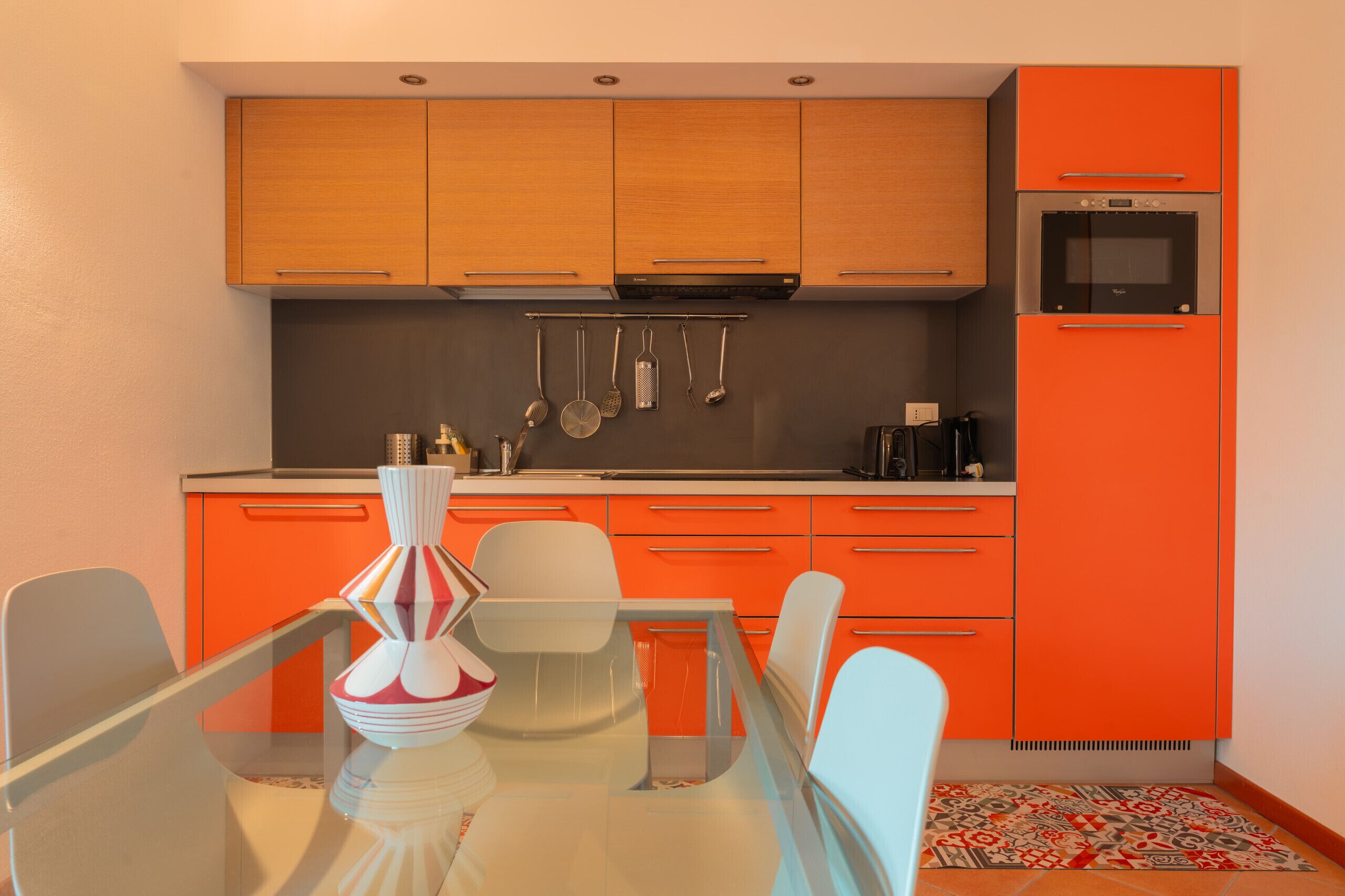Eine moderne Küche mit Holzausbau, einem Glastisch und einem roten Kühlschrank.