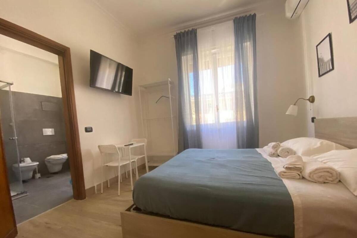 Un dormitorio con cama, televisor, ducha y baño.