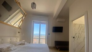 A bedroom with a large bed, a TV, a balcony, and a marble wall.