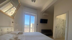 A bedroom with a bed, a TV, a window, and a door.
