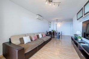 A modern living room with a sofa, dining table, and TV. - Spectacular apartment for 6 with sea views (Benalmádena)