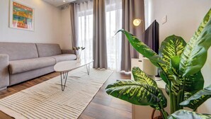 Ein modernes Wohnzimmer mit einer Couch, einem Esstisch und einer großen Pflanze.
