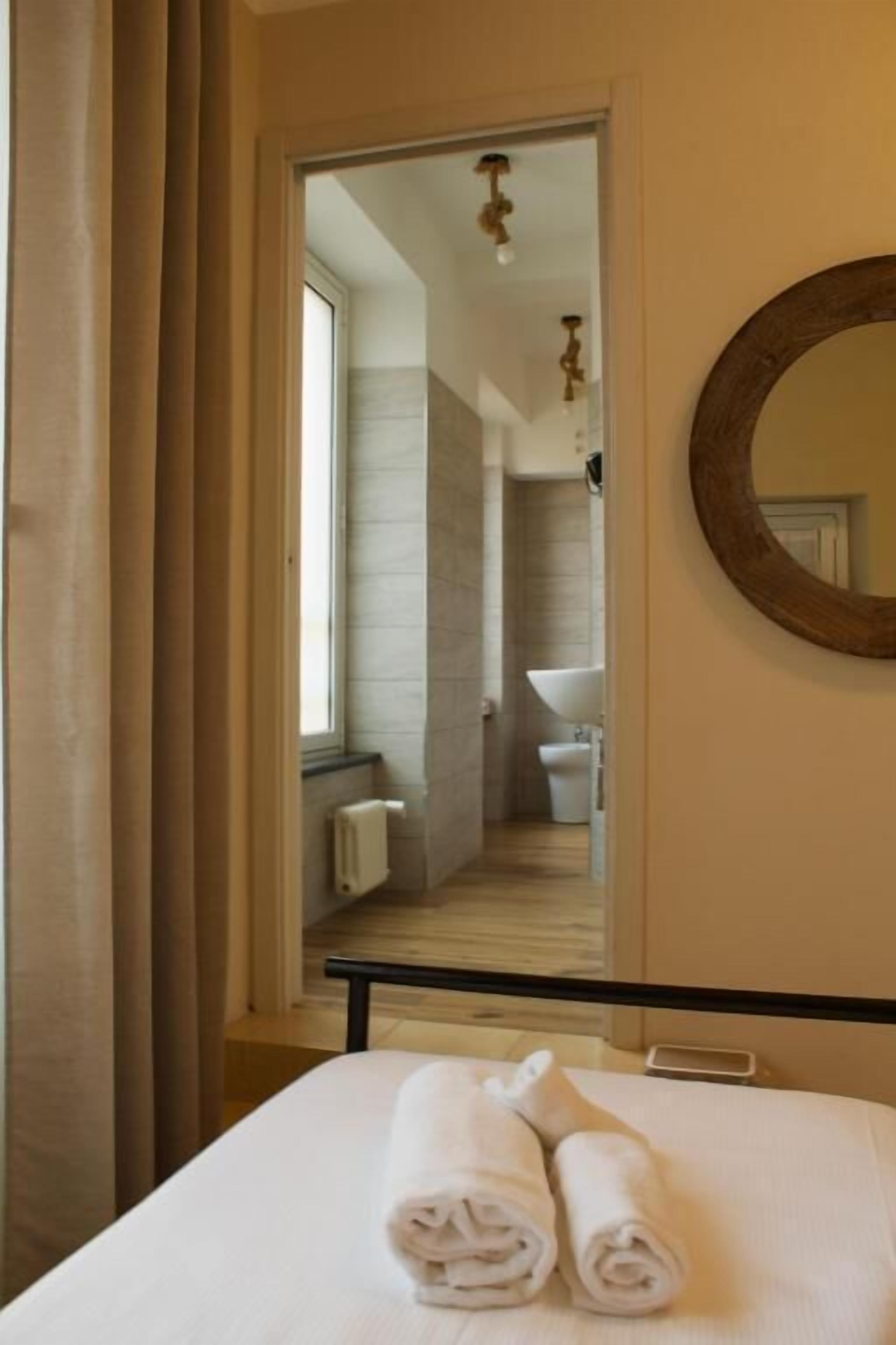 A hotel room with a bed, a mirror, and a view into the bathroom.