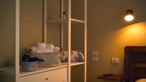 A room with a white wardrobe, a bedside table, a lamp, and a small shelf with toiletries. - Piccolo Borgo (Chiavari)