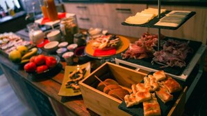 A buffet with various food items and a wooden crate with bread. - Piccolo Borgo (Chiavari)