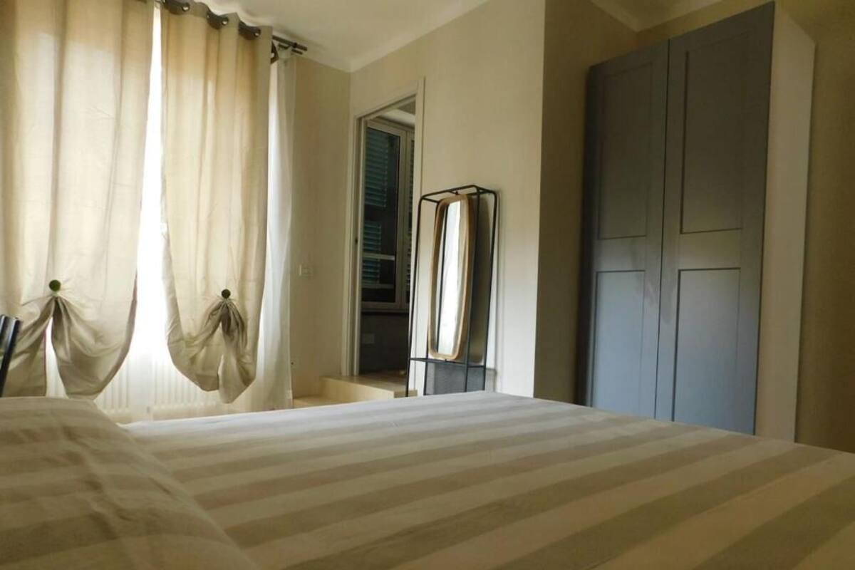 Un dormitorio con cama, cortinas, armario y ventana.