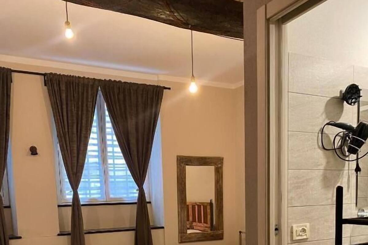 Un dormitorio con dos camas, un espejo, suelo de madera y una puerta que da a un baño.
