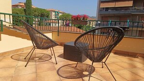 A balcony with two chairs and a table, overlooking a residential area with buildings and a tree. - Piccolo Borgo (Chiavari)