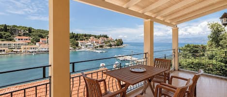 A covered outdoor seating area with a view of a coastal town and the sea.