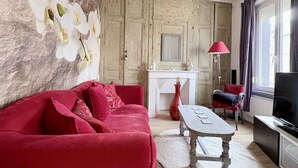 Ein Wohnzimmer mit einem roten Sofa, einem weißen Kamin und einem Fernseher.